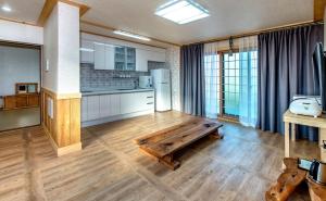 a kitchen with a wooden table in the middle of a room at Bada Maru Pension in Seogwipo