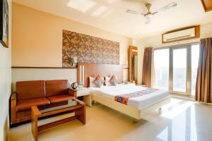 a bedroom with a bed and a couch and a window at FabHotel Devanshi Inn in Kalamboli
