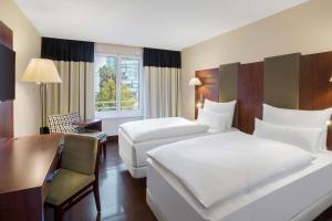 a hotel room with two beds and a desk at NH Vienna Airport Conference Center in Schwechat +39 photos