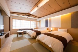 a room with two beds and a television in it at Chaharu in Matsuyama