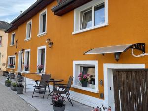 ein orangefarbenes Gebäude mit einem Tisch und Stühlen im Freien in der Unterkunft L'Orange in Scheidgen