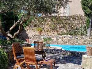 two chairs and a table next to a swimming pool at Le petit château de vacances in Ginestas