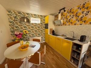 a kitchen with a white table and yellow cabinets at Bungalow at the Beach in Noordwijk aan Zee +10 photos