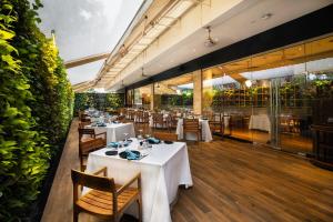 a restaurant with white tables and chairs and plants at Marriott Suites Pune in Pune