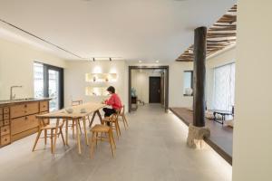 una persona seduta a un tavolo in una cucina di Boro Hanok Hostel in Myeongdong a Seul