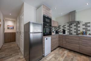 a kitchen with a stainless steel refrigerator and cabinets at Douce Escapade - Balcon - Parking in Jausiers