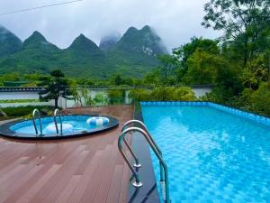una piscina del resort con montagne sullo sfondo di Whispering Retreat a Yangshuo