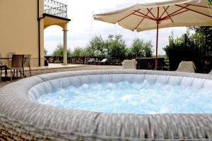 a hot tub with an umbrella next to a patio at Panoramic villa near Florence in Pescia