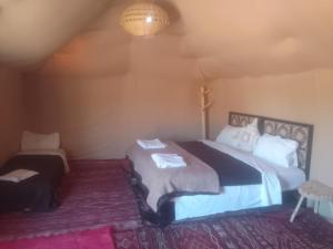 a bedroom with two beds and a cross on the wall at Sahara family camp in Merzouga