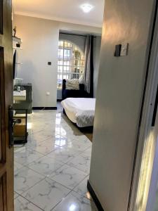 a room with a bed and a room with a tile floor at Yazmin's Bright Studio with Fast Wi-Fi & Parking in Kampala