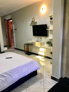 a bedroom with a bed and a flat screen tv at Yazmin's Bright Studio with Fast Wi-Fi & Parking in Kampala