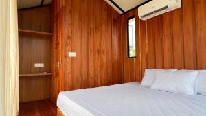 a bedroom with a white bed in a wooden wall at Alpine Zenith - Luxury Wooden Cottages in Meppādi +16 photos