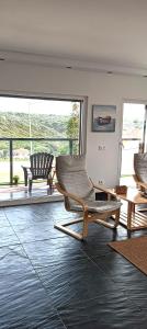 a living room with two chairs and a large window at Zambujeiraseahouse - 100m da praia in Zambujeira do Mar