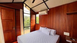a bedroom with a bed and a window at Alpine Zenith - Luxury Wooden Cottages in Meppādi +17 photos