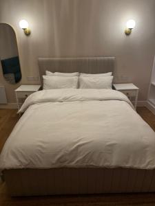 um quarto com uma cama grande com lençóis e travesseiros brancos em Peckham Haven em Londres