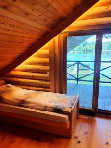 a bed in a room with a large window at Atostogų namelis ant ežero kranto in Juočionys