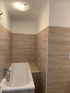 a bathroom with a white tub and wooden walls at Panda apartman in Esztergom +17 photos