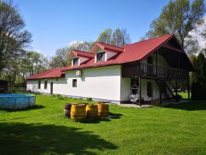 a white house with a red roof and some barrels at Ranč Nová Zem in Blatná Polianka