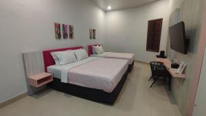 a bedroom with two beds and a television in it at Hayak Tamara Syariah Hotel in Muaratewe