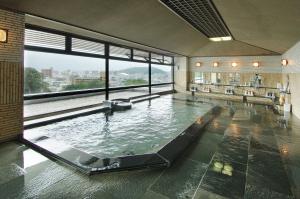 ein großer Pool in einem Gebäude mit einem großen Fenster in der Unterkunft Chaharu in Matsuyama