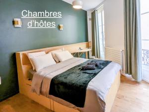 a bedroom with a bed with a sign on the wall at Ômarais Guest House in Paris