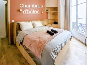 a bedroom with a bed with two black shoes on it at Ômarais Guest House in Paris