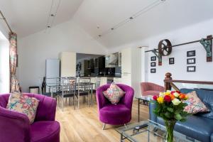a living room with purple chairs and a table at Merok Mill House & Old Granary in Six Road Ends