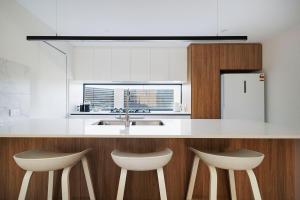 a kitchen with a counter with two chairs and a sink at Urban Haus - Hillarys in Perth