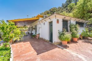 a white house with potted plants in front of it at Casa Rural Puente Piedra in Carcabuey