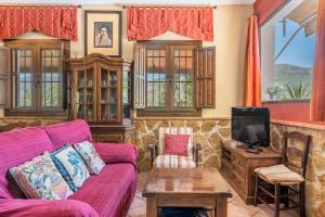 a living room with a purple couch and a tv at Casa Rural Puente Piedra in Carcabuey