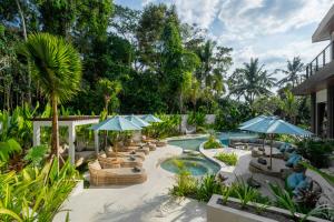 a resort with a pool with umbrellas and chairs at Villa Baliga Ubud by BaliSuperHost in Ubud