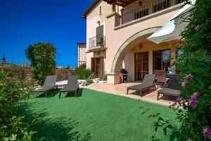 a yard with chairs and a house at 2 bedroom Apartment Artemis with two communal pools, Aphrodite Hills Resort in Kouklia