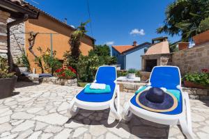 twee blauwe stoelen met hoeden erop op een terras bij St. Bernhard House in Funtana