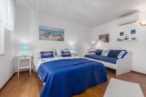 een witte slaapkamer met een blauw bed en een bank bij St. Bernhard House in Funtana +38 foto's