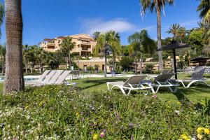 a group of lounge chairs and an umbrella next to a pool at Quartiers Marbella Golden Penthouse in Benahavís