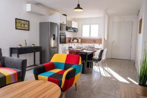 a living room with a colorful chair and a kitchen at La Giroussinaise in Giroussens