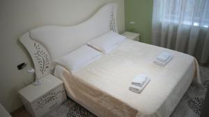 a bedroom with a white bed with two towels on it at Paris's Apartment in Gjirokastër
