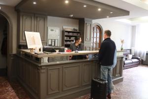 two people standing at a counter in a store at Hôtel Le Lons in Foix