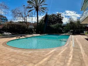 a swimming pool in a yard with a palm tree at Apartament Mar Beach Lloret II Aqua in Lloret de Mar