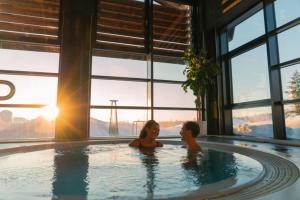 a man and woman sitting in a hot tub with the sun at Skogro ved Norefjell in Noresund +25 photos