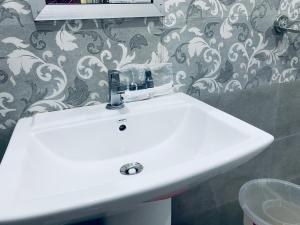 Gupta KāshiHotel Rajshree Palace的浴室内有白色水槽,配有壁纸