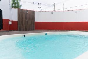 a large swimming pool with a red and white wall at Recanto dos Pássaros Refúgio com piscina e lazer in Pôrto Feliz
