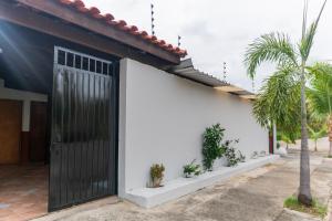 a white house with a black door and potted plants at Recanto dos Pássaros Refúgio com piscina e lazer in Pôrto Feliz
