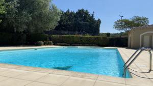 a swimming pool with blue water in a yard at Le Mazet du Moulin in Mouriès