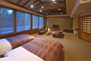 a bedroom with two beds and a tv and windows at Kusatsu Skyland Hotel in Kusatsu