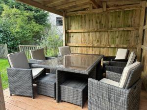 バクストンにあるCLIFTON BANK - Characterful & Cosy Home in Buxton, Peak Districtのガラステーブルと籐の椅子付きのパティオ