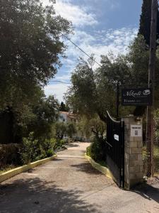 a street with a gate and a sign on a fence at Nikoli Apartments in Benitses