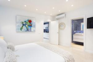 a white bedroom with a bed and a painting on the wall at La Tortuga Azul A in Puerto de la Cruz