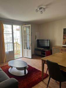 a living room with a couch and a table and a tv at Appartement au coeur de Saumur - Chambre climatisée in Saumur