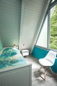 a bed and a chair in a room with a window at Ferienhaus Waldperle in Ronshausen